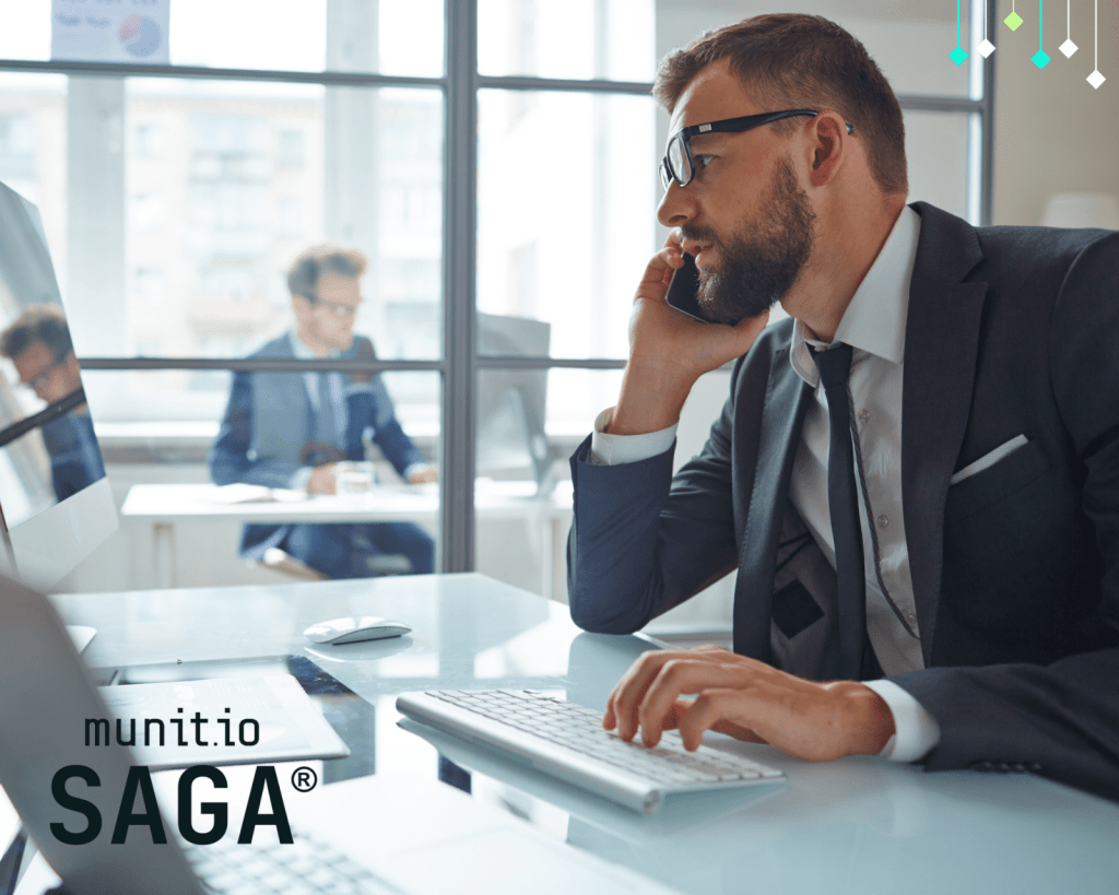 A business executive in a suit works at his computer while speaking on the phone, highlighting the high-stakes environment where understanding what is executive protection becomes essential for safeguarding leadership and sensitive operations.