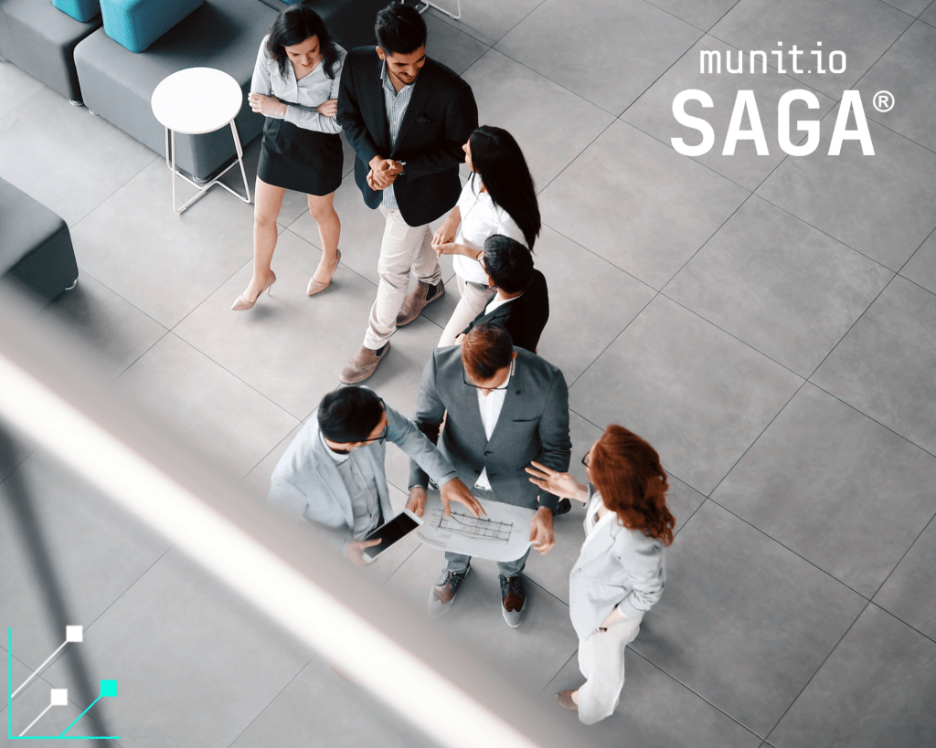 Group of business professionals gathered in a discussion around a floor plan in an office lobby, illustrating collaboration to overcome a Market Intelligence Silo.