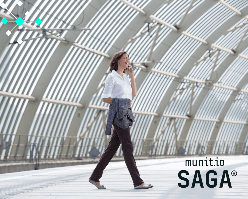 A business professional walking while talking on a smartphone inside a modern glass-covered walkway, illustrating How to detect fake support accounts that often target users through mobile communication channels.