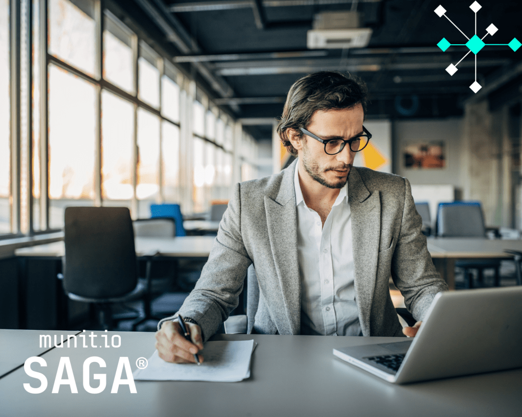 A business professional reviewing information on a laptop while taking notes in a modern office, illustrating Brand abuse monitoring on social media through active analysis and digital threat assessment.