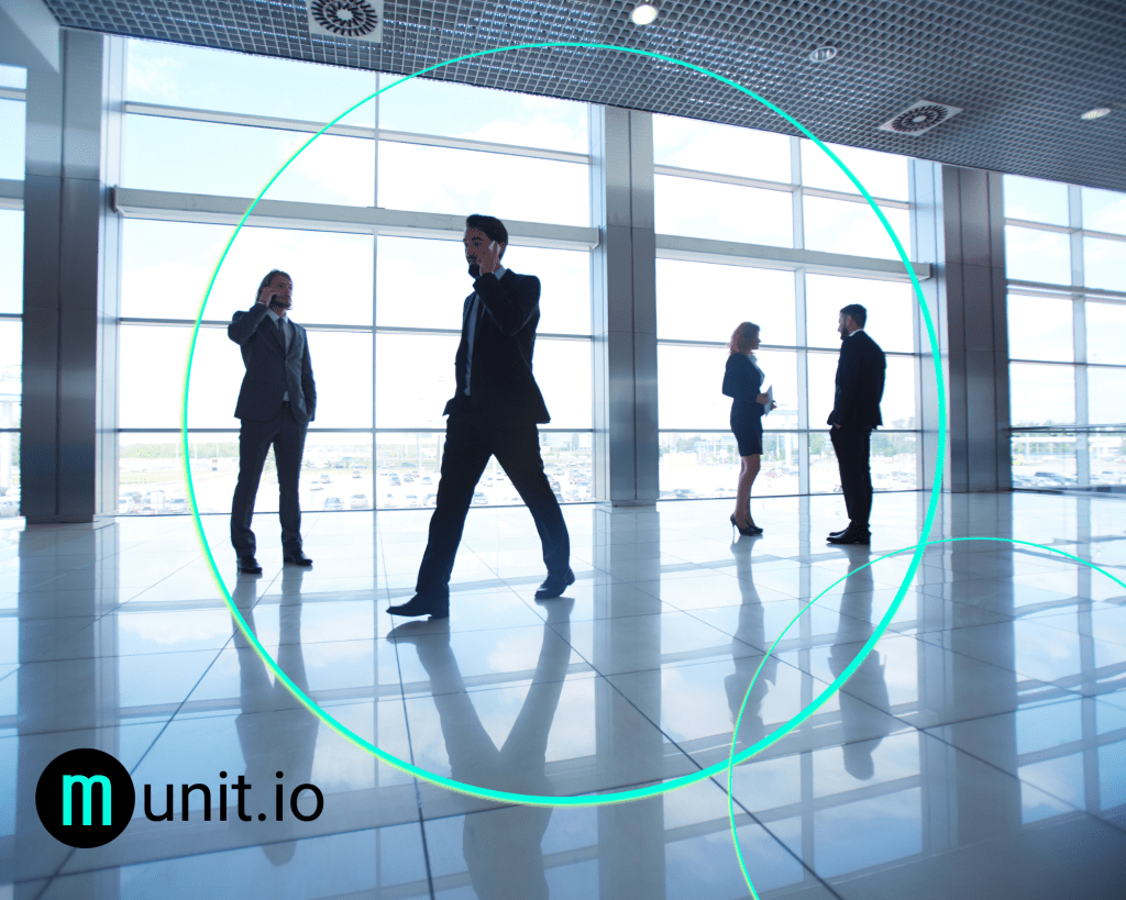 Business professionals walking and talking on smartphones inside a large glass office space, illustrating How fraudsters imitate companies online by mimicking legitimate corporate communication and behavior.